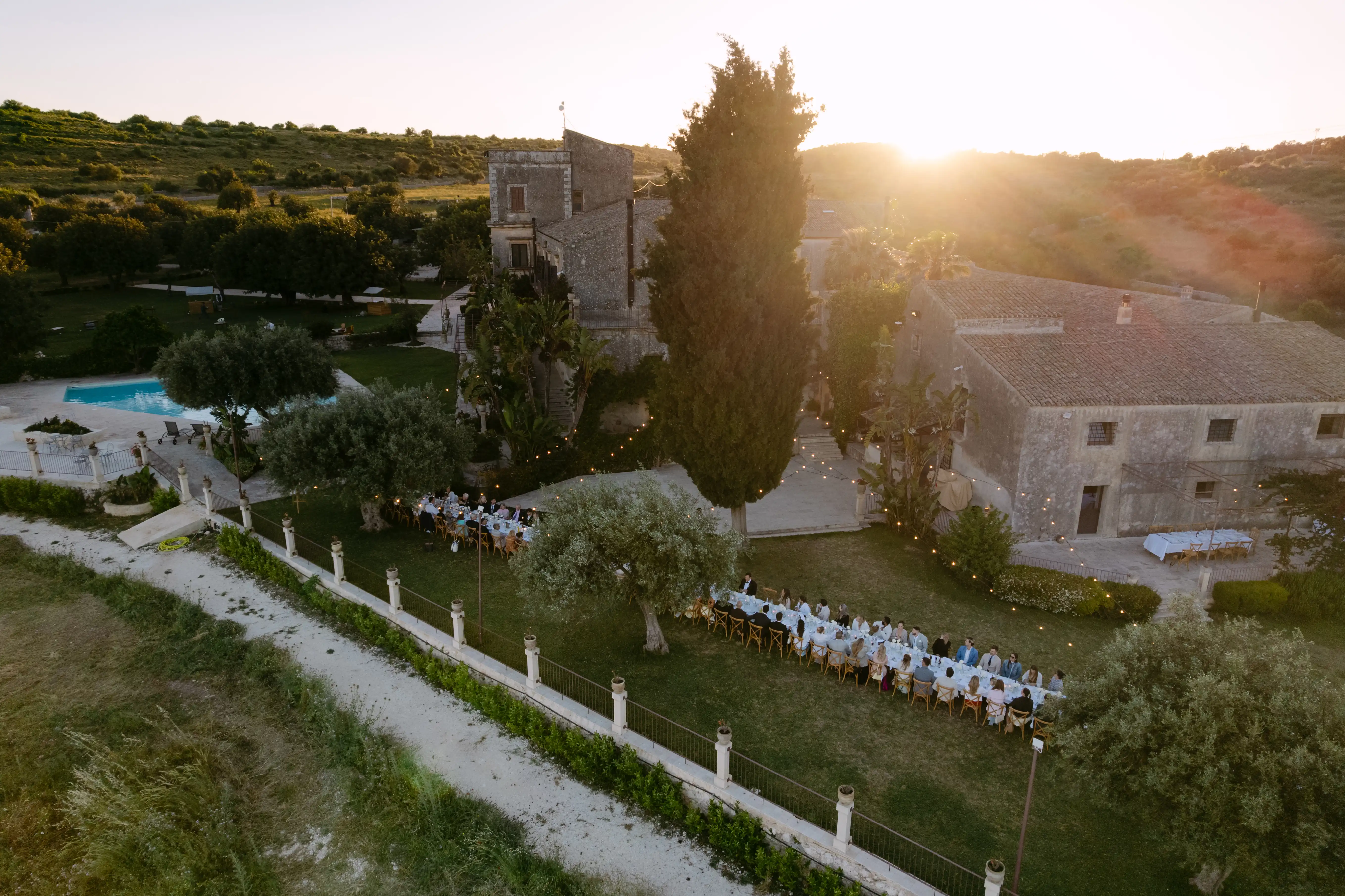 Aerial drone view of a luxury wedding reception at a historic countryside villa in Sicily at sunset.